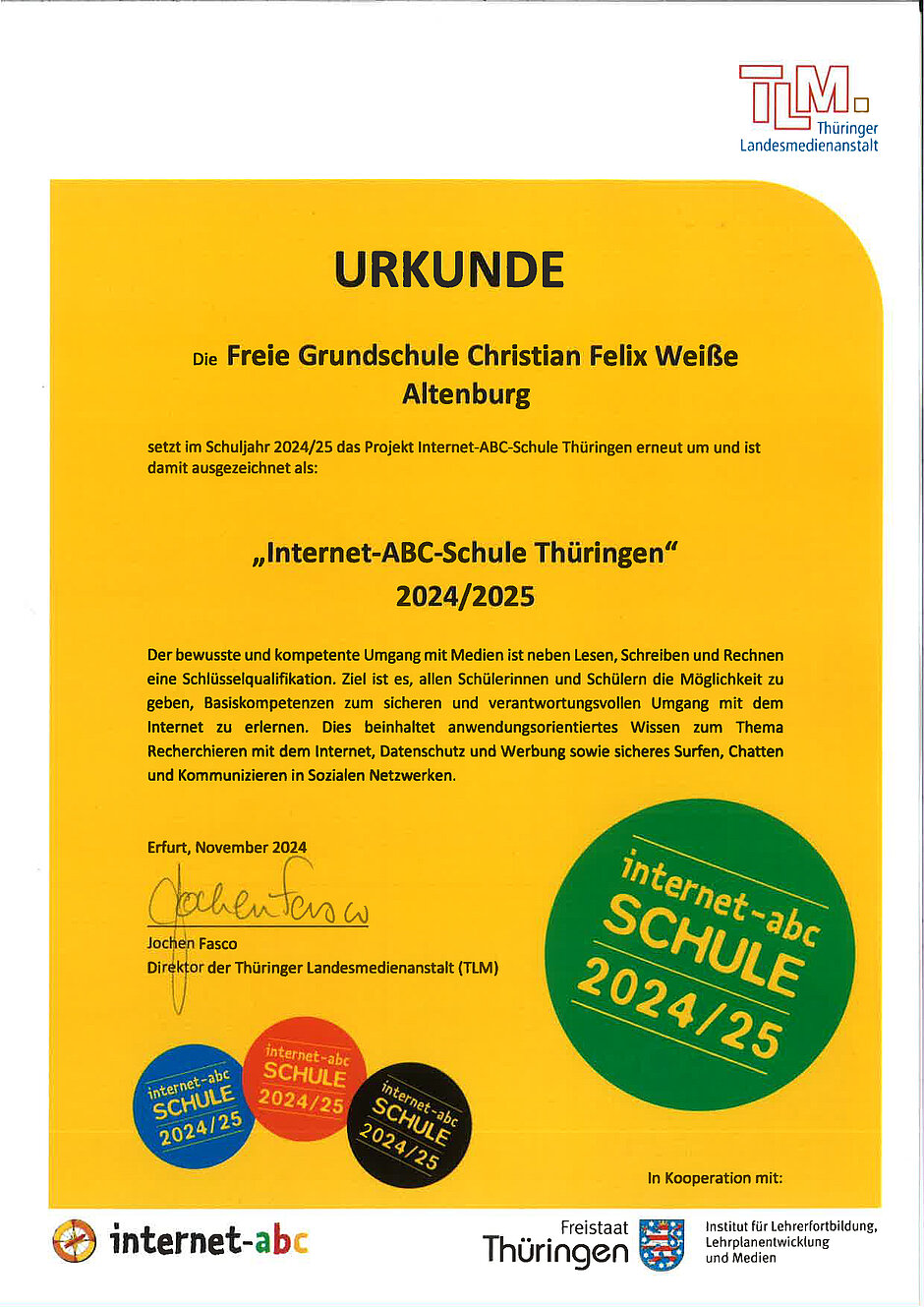 Eine gelbe Urkunde zeichnet die Grundschule als Internet-ABC-Schule Thüringen 2024/2025 aus. Ausgestellt wurde sie von der Thrüinger Landesmedienanstalt verweist auf den bewussten und kompetenten Umgang mit Medien an der Freien Grundschule.